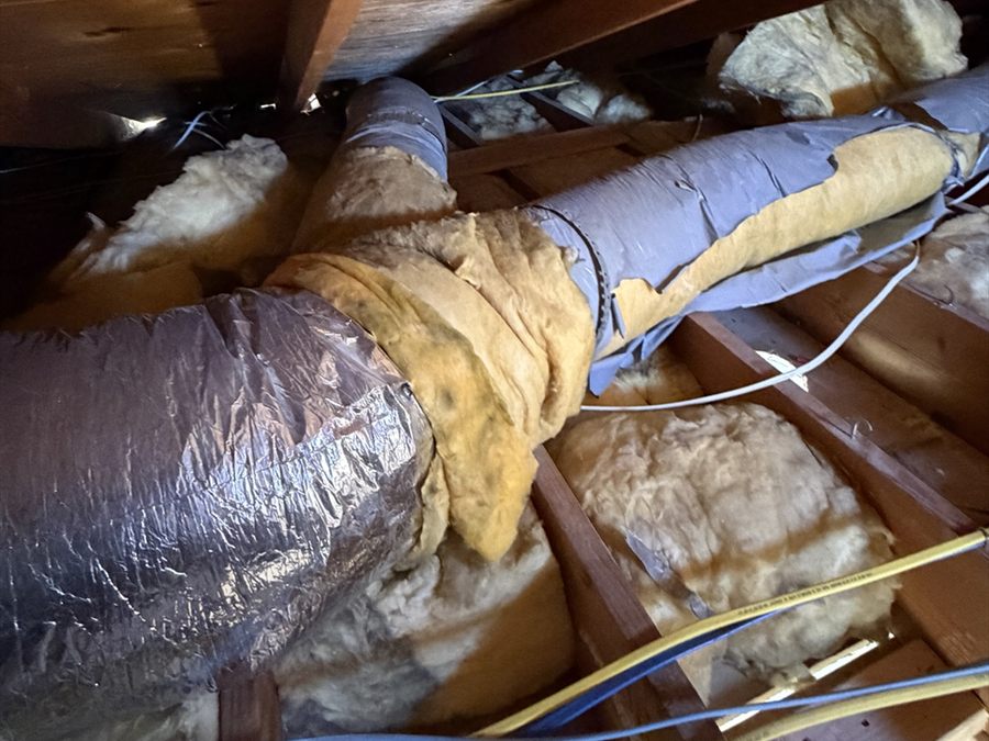 Damaged attic ductwork with torn insulation and exposed duct material