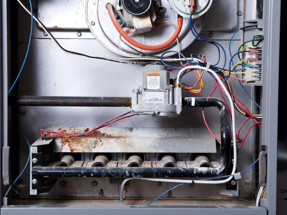 Inside a gas furnace during a heating repair: gas valve, burners and wiring