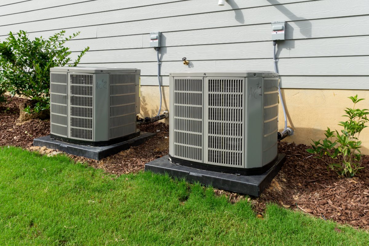 Two outdoor condensing units on pads beside a home
