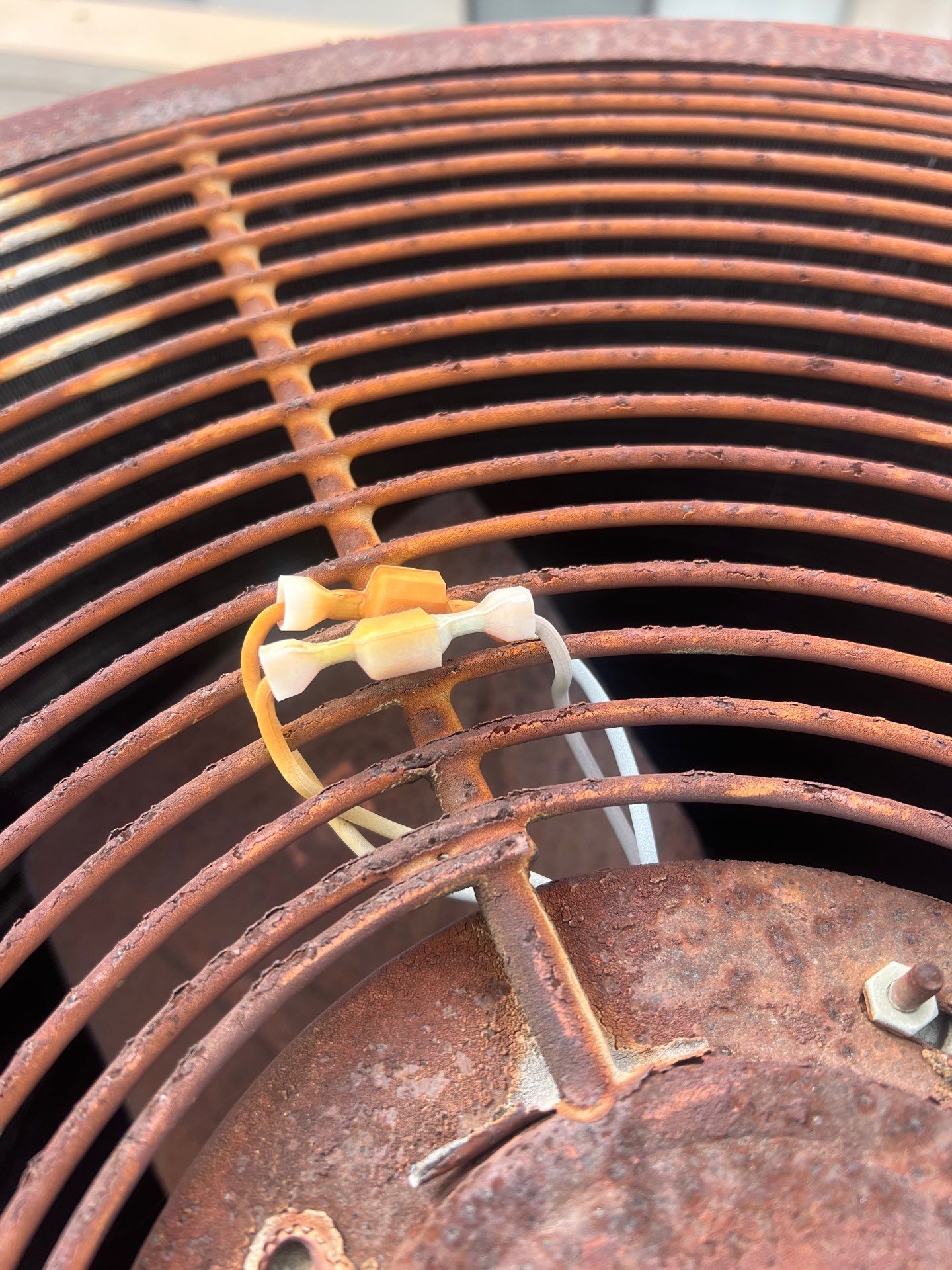 Close-up of a heavily rusted AC condenser, the kind of aging unit that prompts a repair-or-replace decision in Orange County