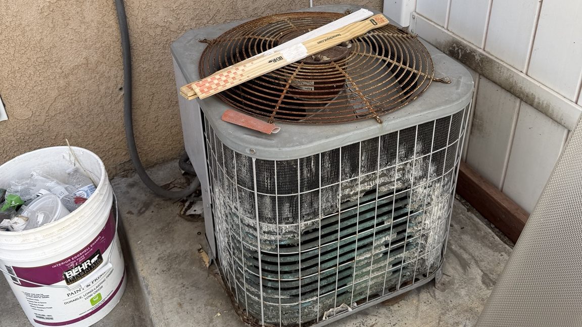 Older weathered air conditioning condenser being evaluated for repair or replacement